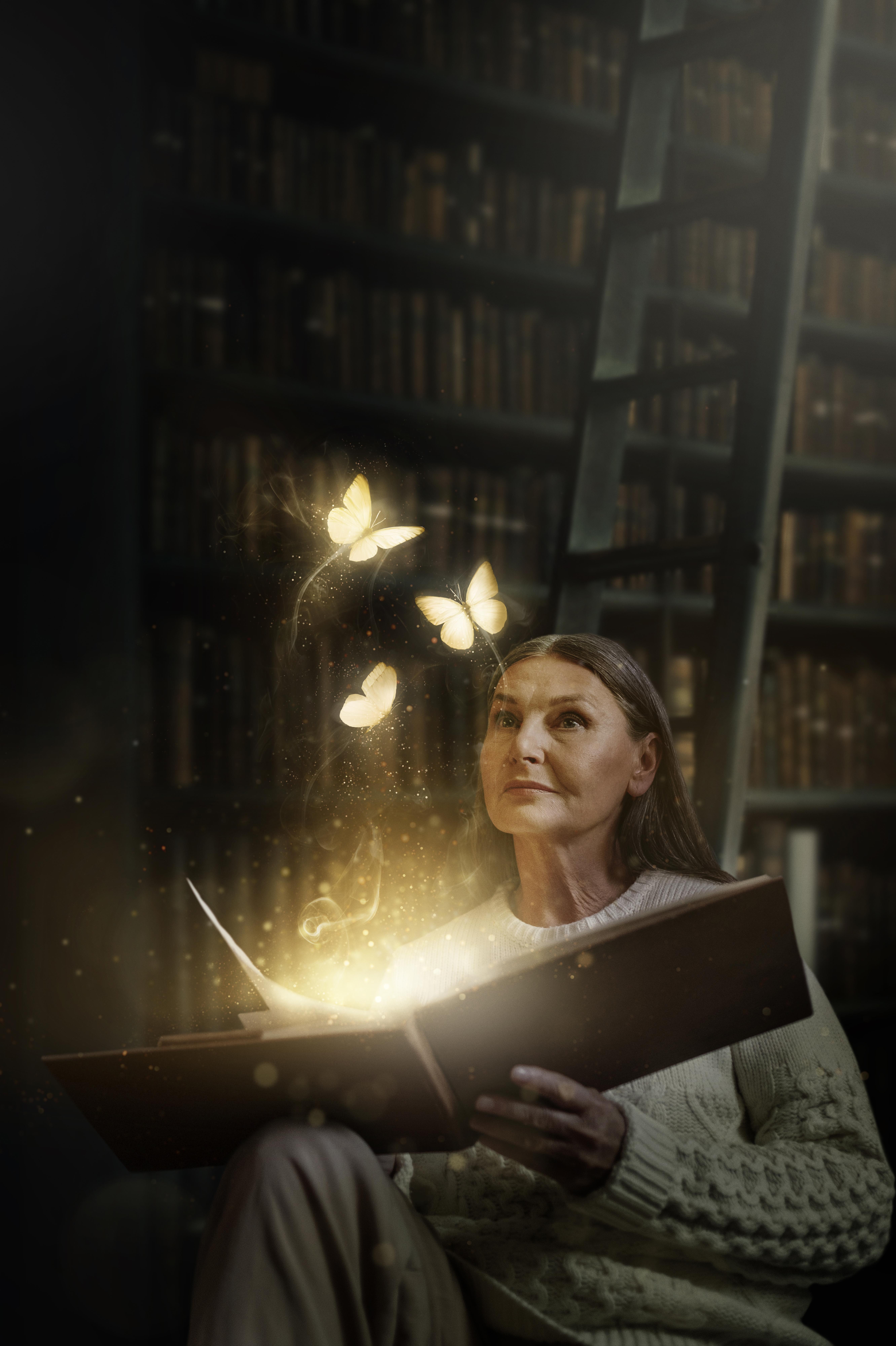 Femme tenant un livre lumineux entouré de papillons, évoquant l’ouverture aux mémoires de l’âme et aux Annales Akashiques.