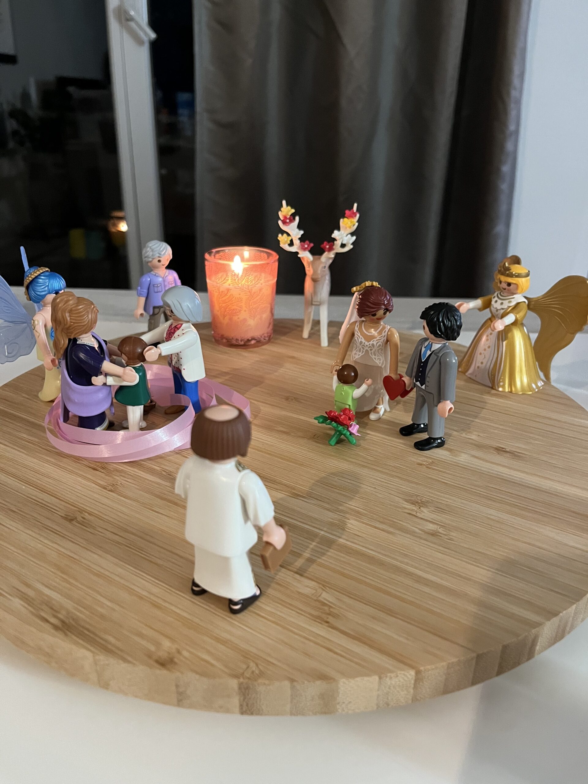 Figurines représentant une constellation familiale individuelle disposées en cercle autour d’une bougie.